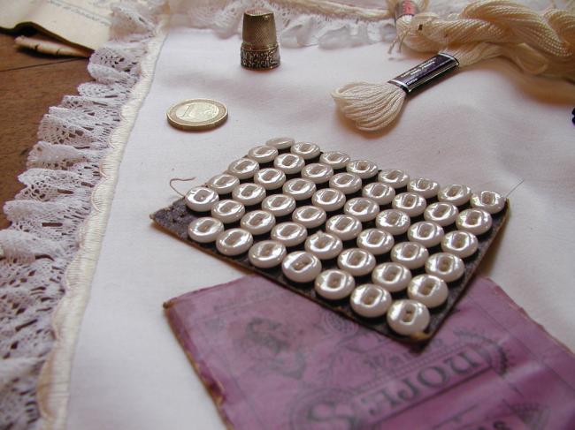 Série de 48 boutons ronds dits 'viennois'en verre blanc irisé, 2 trous,sur carte