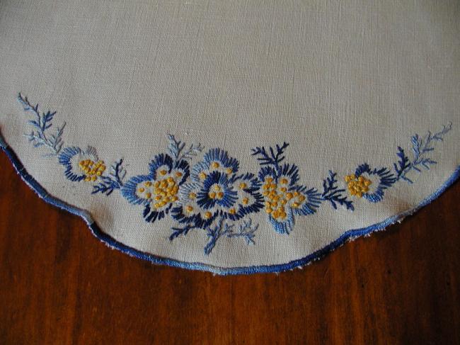 Charming blue and yellow gold embroideries on a linen doily.