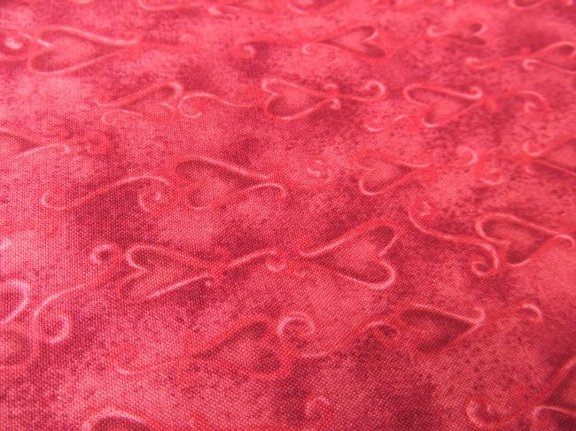 Coupon de coton à fond rouge grenat avec impression de coeurs stylisés